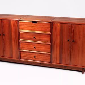 Front view of a solid redwood credenza with 3 drawers in the center and a storage cabinet on either side of the drawers. The piece can function as a sideboard or turntable cabinet. It has a lift top opening in the top to hold either serving accoutrement or a turntable. Built using hand-tools from solid redwood with pine sided drawers, by Marc Springer woodworker and furniture maker.