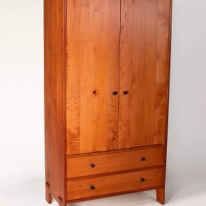 A large, solid wood armoire with hanging space above and two drawers on the bottom.