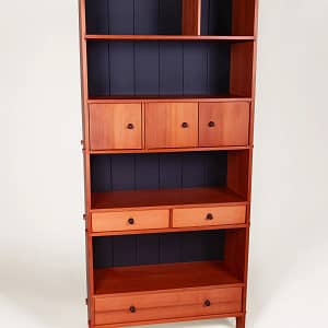 A western red cedar bookcase with 4 bookshelves, a large full-width bottom drawer, a row of two smaller drawers and a cabinet section with three doors that span the width of the case.This bookcase was milled, joined and crafted using only hand tools and traditional wood joinery. The case and fronts are crafted from western red cedar. It is joined at the top with dovetails and the shelves and drawer housings are either pinned into rabbets with walnut dowels, or with through mortise and tenons which are then splined. All the drawers are dovetailed with pine sides, solid wood bottoms and custom turned walnut knobs. The back is hand crafted tongue and groove made from solid pine, finished in several coats of matte black with a final coat of dead flat overcoat. All hardware, hinges for the cabinets and screws for the back are brass. The entire cabinet is finished with 5 coats of hand-rubbed finished with a final beeswax polish.The case is 32" wide, 14" deep and 72" high. The piece was designed and crafted by Marc Springer a furniture maker in Woodland Hills, California.