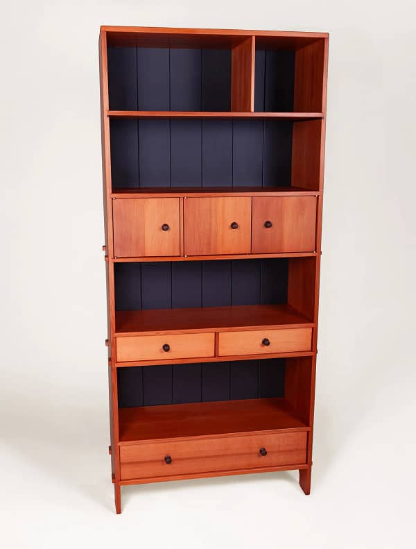 A western red cedar bookcase with 4 bookshelves, a large full-width bottom drawer, a row of two smaller drawers and a cabinet section with three doors that span the width of the case.This bookcase was milled, joined and crafted using only hand tools and traditional wood joinery. The case and fronts are crafted from western red cedar. It is joined at the top with dovetails and the shelves and drawer housings are either pinned into rabbets with walnut dowels, or with through mortise and tenons which are then splined. All the drawers are dovetailed with pine sides, solid wood bottoms and custom turned walnut knobs. The back is hand crafted tongue and groove made from solid pine, finished in several coats of matte black with a final coat of dead flat overcoat. All hardware, hinges for the cabinets and screws for the back are brass. The entire cabinet is finished with 5 coats of hand-rubbed finished with a final beeswax polish.The case is 32" wide, 14" deep and 72" high. The piece was designed and crafted by Marc Springer a furniture maker in Woodland Hills, California.